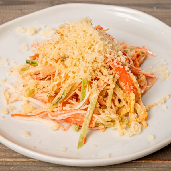 Hana Hawaiian BBQ's crab salad with shredded crab, cucumber, and crispy tempura flakes on a white plate.