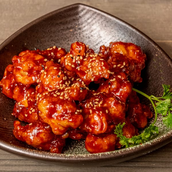 Hana Hawaiian BBQ's sweet and spicy chicken bites, garnished with sesame seeds and parsley.